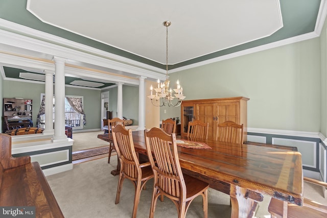 dining space with light colored carpet, an inviting chandelier, ornamental molding, and ornate columns