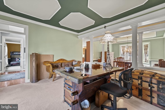 carpeted dining space with crown molding, a notable chandelier, and decorative columns