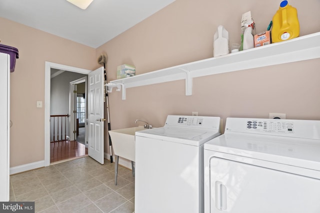 laundry area featuring a sink, separate washer and dryer, light tile patterned flooring, baseboards, and laundry area