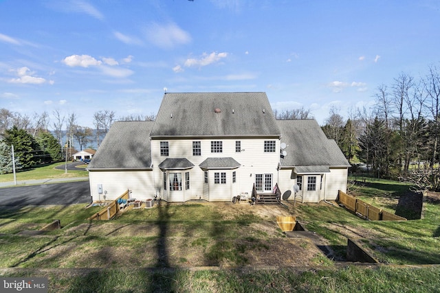 back of property featuring entry steps, a lawn, fence, and a shingled roof