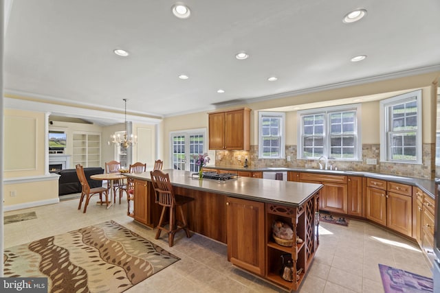 kitchen featuring dark countertops, a kitchen island, crown molding, stainless steel gas cooktop, and dishwasher