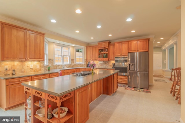 kitchen featuring open shelves, a kitchen island, appliances with stainless steel finishes, crown molding, and decorative columns