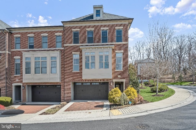 multi unit property with a garage and brick siding