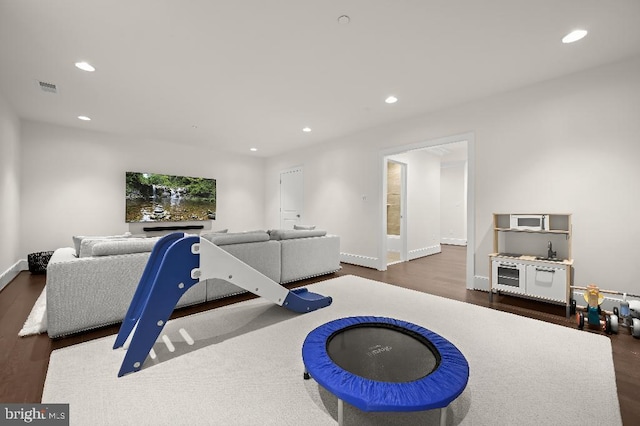 workout area featuring dark wood finished floors, visible vents, recessed lighting, and baseboards