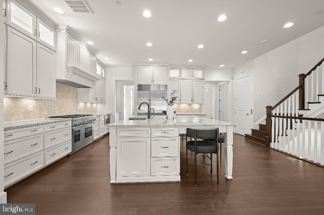 kitchen featuring dark wood finished floors, recessed lighting, a sink, white cabinetry, and high quality appliances