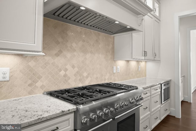 kitchen featuring decorative backsplash, white cabinetry, custom range hood, and range with two ovens