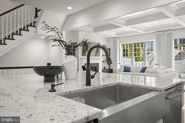 kitchen with coffered ceiling, recessed lighting, a sink, a lit fireplace, and beamed ceiling