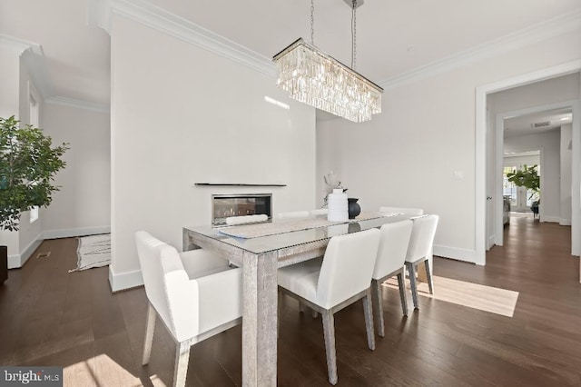 dining area with baseboards, ornamental molding, and dark wood finished floors