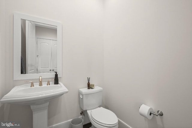 half bath with baseboards and toilet