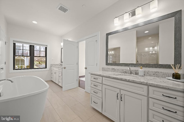 bathroom featuring tile patterned floors, a freestanding tub, visible vents, and vanity