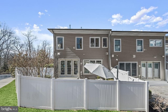 back of property featuring french doors and fence