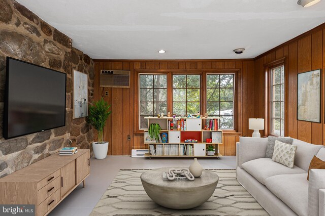 living area with wood walls, a wall mounted air conditioner, and a baseboard radiator