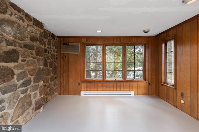 unfurnished room featuring baseboard heating, wood walls, and a wall unit AC