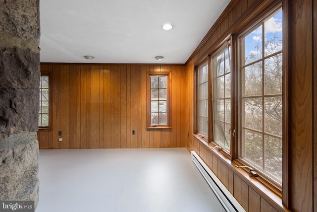 empty room with plenty of natural light, wood walls, and a baseboard radiator