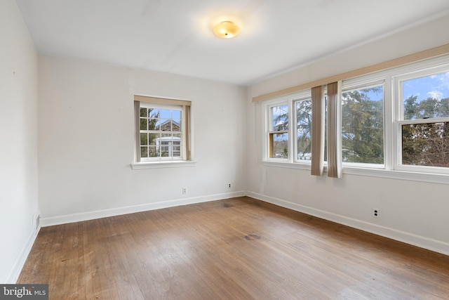 spare room featuring baseboards and wood-type flooring