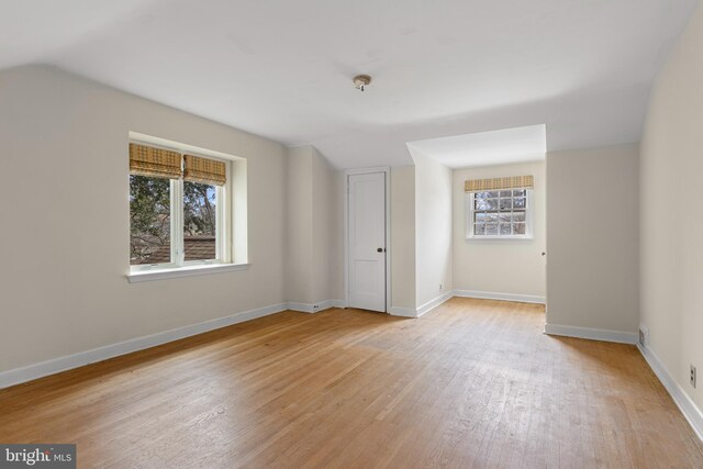 unfurnished bedroom featuring lofted ceiling, light wood-style floors, and baseboards