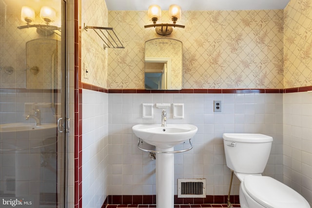 bathroom featuring a wainscoted wall, visible vents, wallpapered walls, a stall shower, and toilet