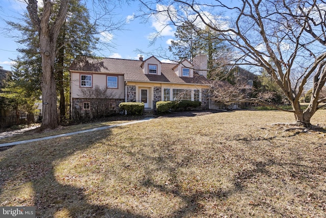 view of front of home with stone siding, a front lawn, and a chimney