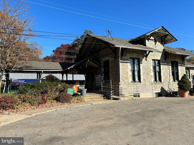 view of home's exterior with stone siding and roof with shingles