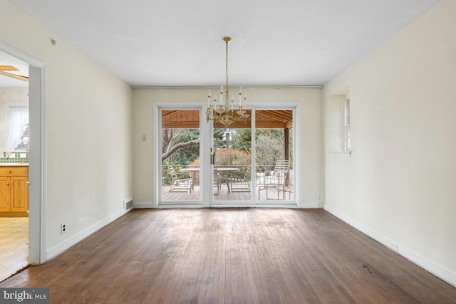 unfurnished dining area featuring visible vents, an inviting chandelier, baseboards, and wood finished floors