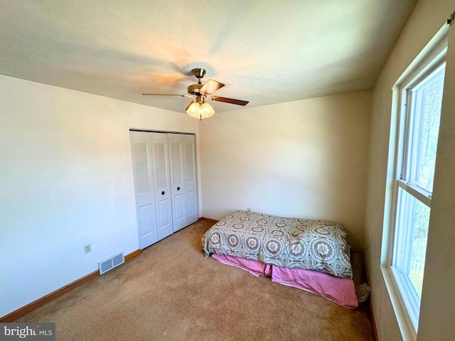 bedroom with visible vents, ceiling fan, baseboards, carpet floors, and a closet