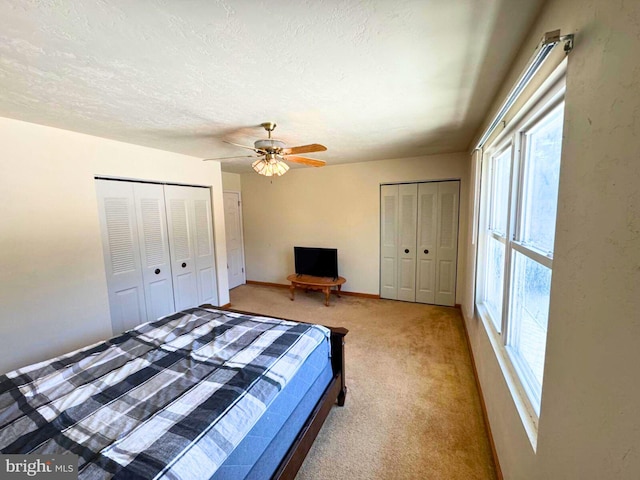 unfurnished bedroom with baseboards, light colored carpet, a textured ceiling, and a ceiling fan