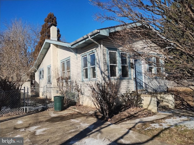 view of property exterior with entry steps, a chimney, and fence