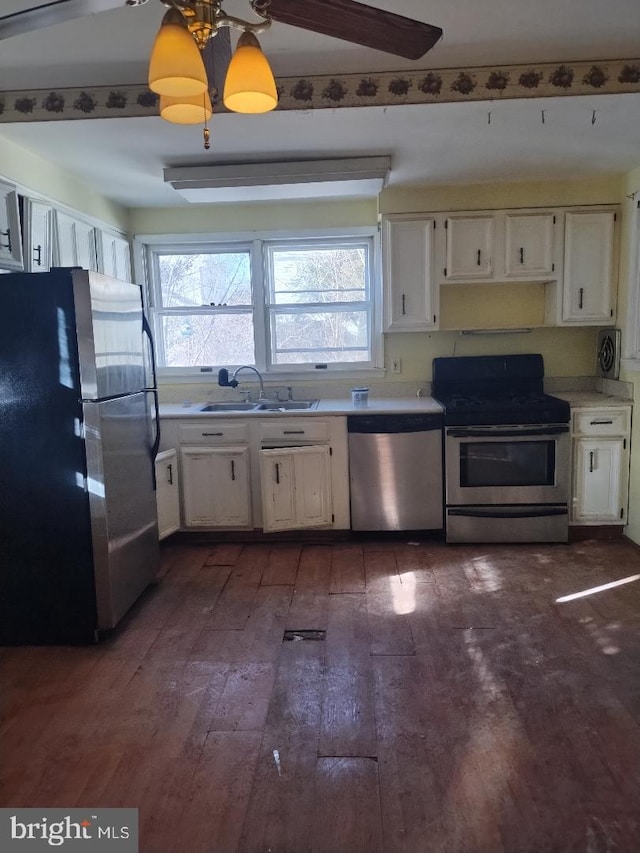 kitchen with appliances with stainless steel finishes, white cabinetry, dark wood-type flooring, and a sink