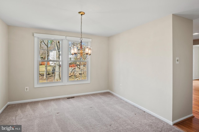 unfurnished dining area featuring an inviting chandelier, baseboards, and carpet floors