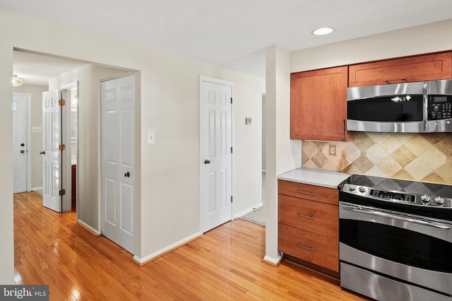 kitchen with stainless steel appliances, decorative backsplash, light countertops, light wood-style floors, and brown cabinets