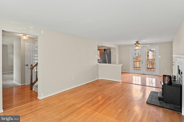 living room with stairway, wood finished floors, baseboards, a fireplace, and ceiling fan