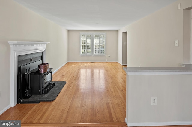 living area with a wood stove, wood finished floors, and baseboards