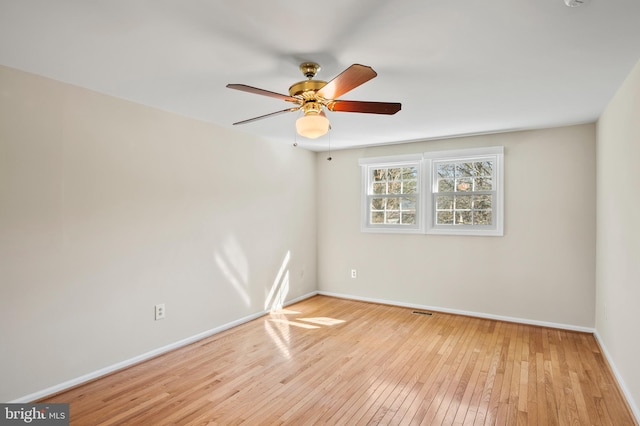 unfurnished room with baseboards, hardwood / wood-style floors, and a ceiling fan