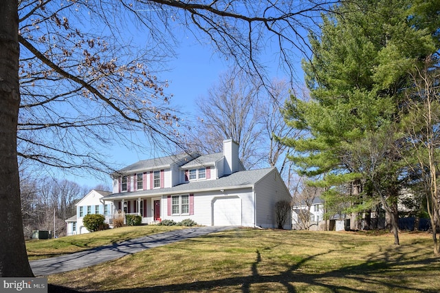 view of front of property with aphalt driveway, a garage, a chimney, and a front yard