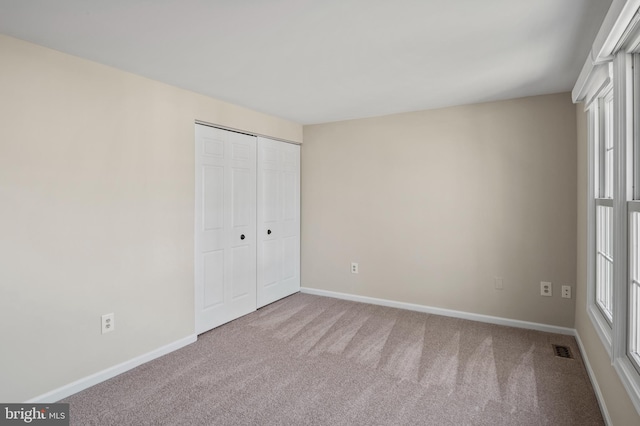 unfurnished bedroom with a closet, visible vents, carpet flooring, and baseboards