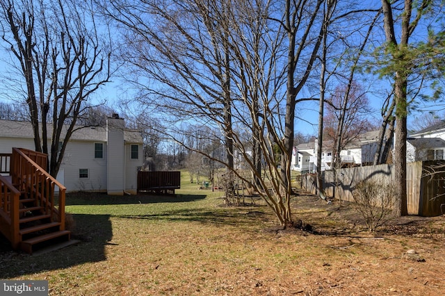 view of yard featuring a deck, stairway, and fence