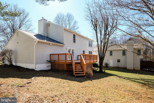 rear view of house with a shingled roof, a lawn, a chimney, and a wooden deck