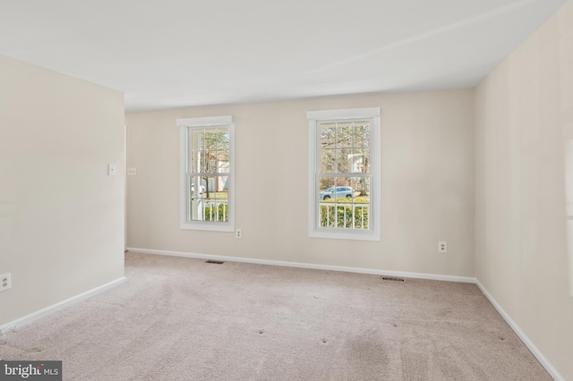 carpeted spare room featuring visible vents and baseboards