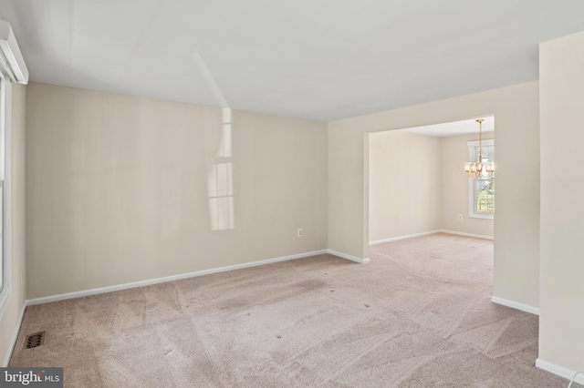 unfurnished room with visible vents, baseboards, an inviting chandelier, and carpet flooring