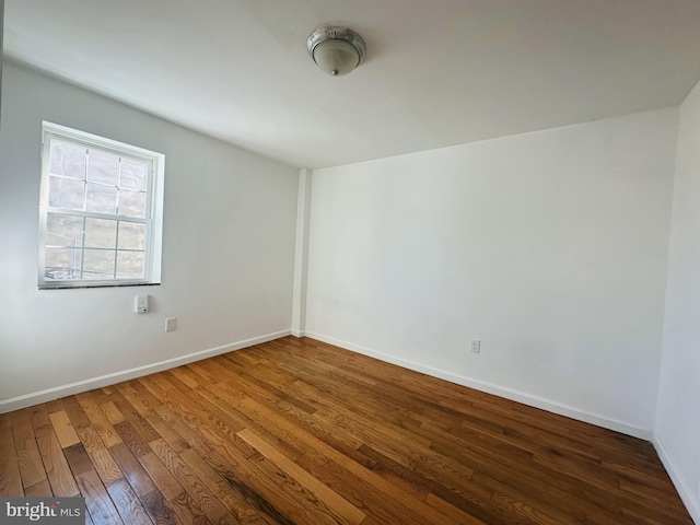 empty room featuring baseboards and wood-type flooring