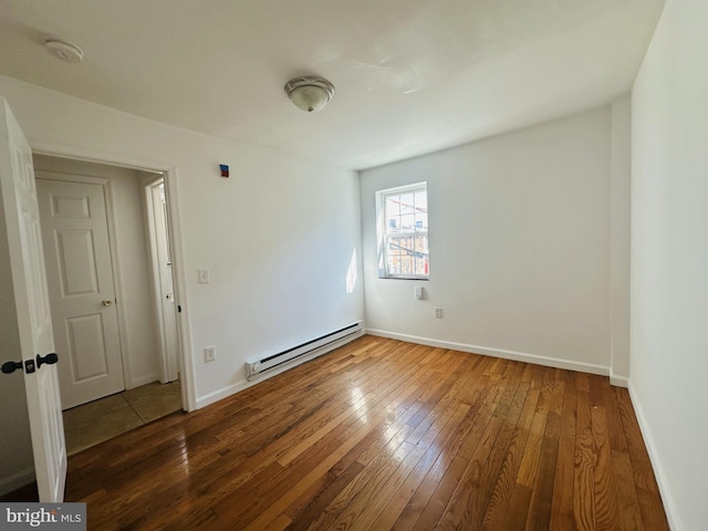 empty room with baseboards, baseboard heating, and hardwood / wood-style floors