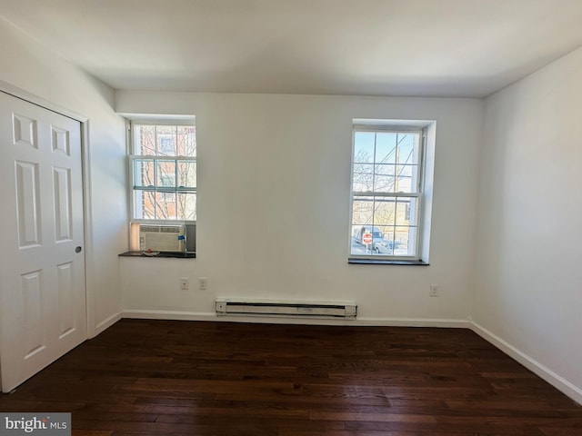 unfurnished room featuring a baseboard heating unit, cooling unit, dark wood-style floors, and baseboards