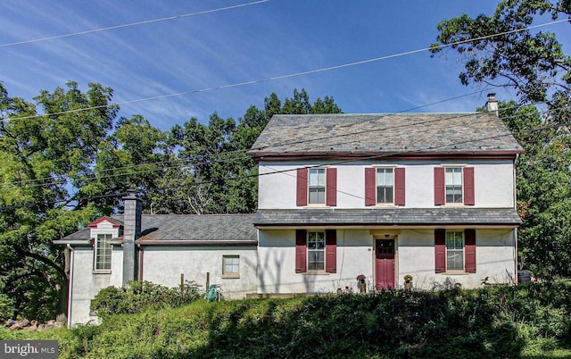 view of front of home with a high end roof, stucco siding, and a chimney