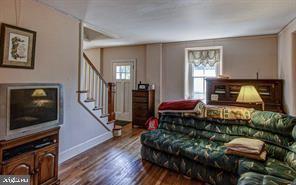 living area with stairway, baseboards, and wood finished floors