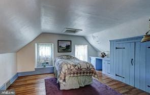 unfurnished bedroom featuring visible vents, baseboards, wood finished floors, and vaulted ceiling