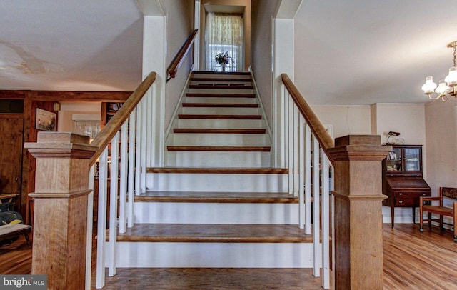 staircase with a chandelier and wood finished floors