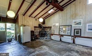 interior space featuring high vaulted ceiling, beamed ceiling, wooden walls, and a wood stove