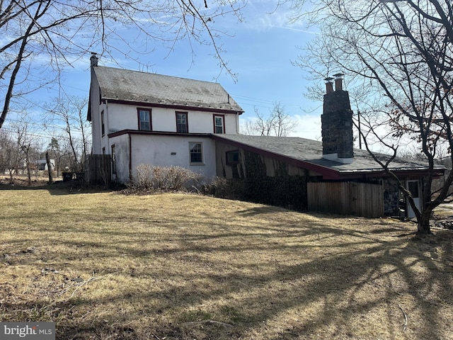 rear view of property with a chimney and a yard