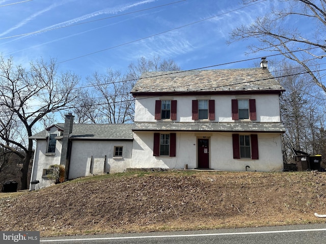 view of front of home featuring a high end roof, stucco siding, and a chimney