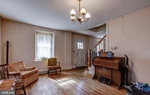 living area with stairway, wood finished floors, and a chandelier